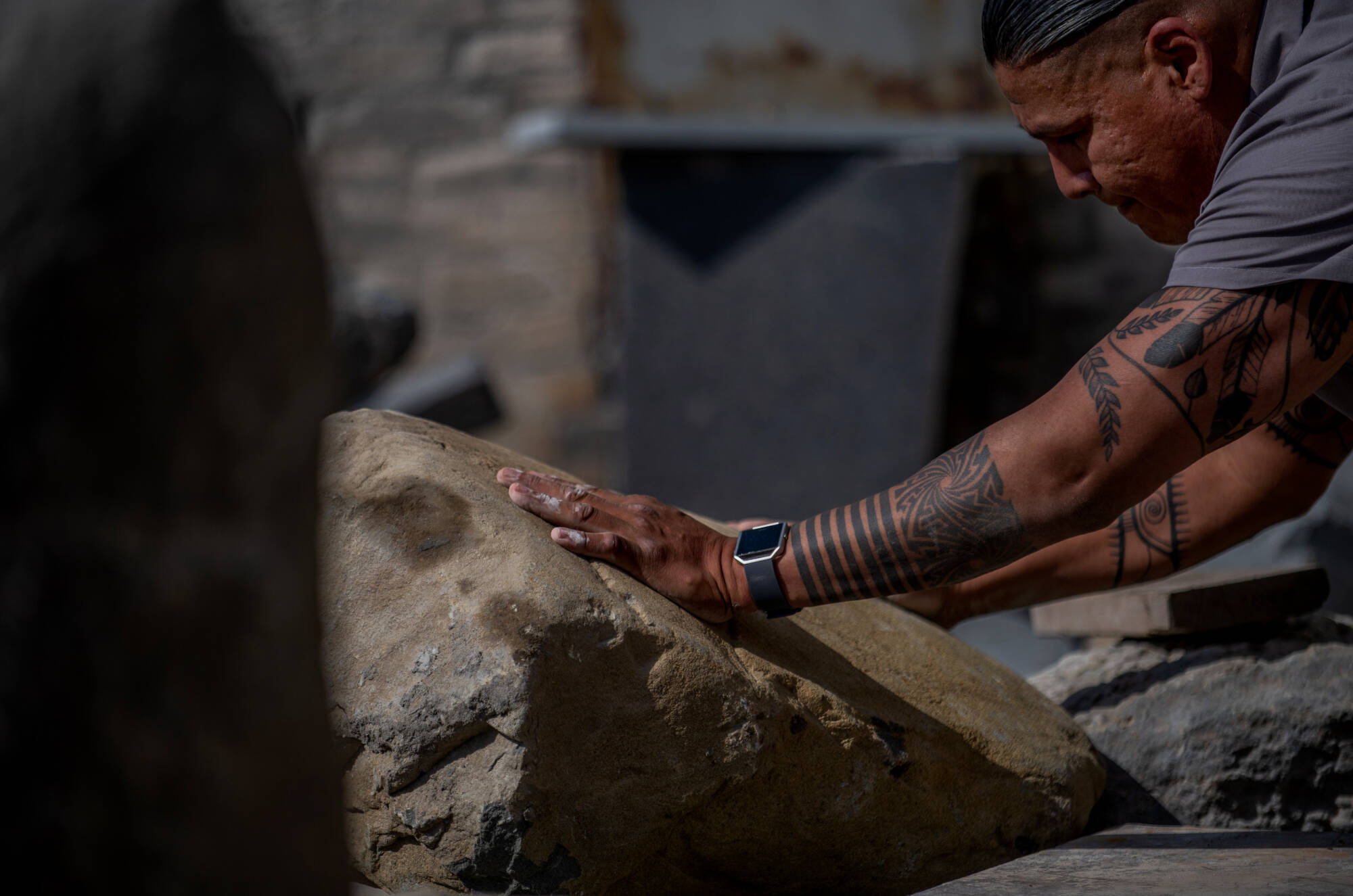 Artist Jason Quigno touches a large stone as he prepares for carving.
